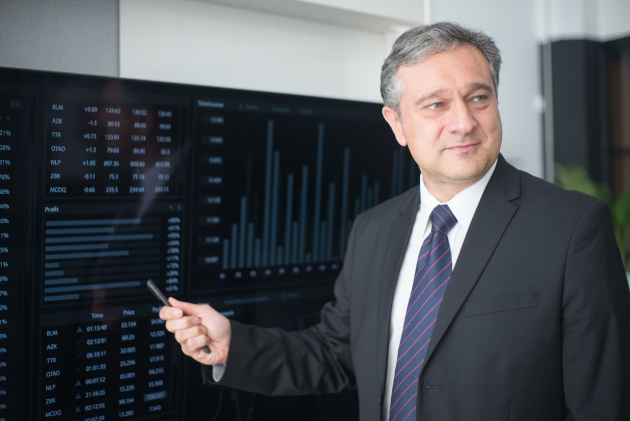 Professionista davanti a uno schermo con grafici finanziari