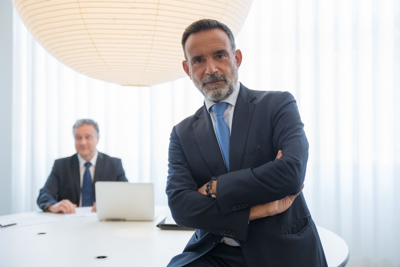 Consulente in abito scuro a braccia incrociate in una sala riunioni